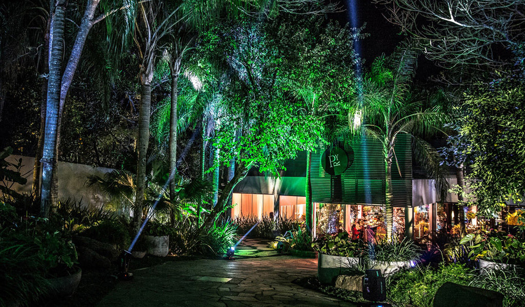 Alameda de entrada à noite, com as palmeiras sob luz verde